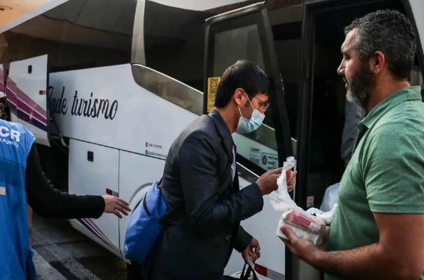 Cinco ônibus com afegãos refugiados estão parados na Rodovia Anchieta após a Prefeitura de Praia Grande recusar abrigo