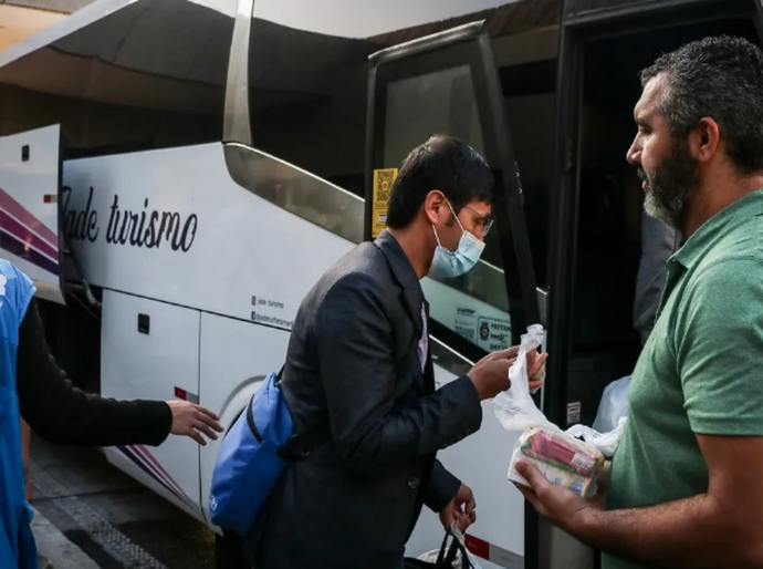 Cinco ônibus com afegãos refugiados estão parados na Rodovia Anchieta após a Prefeitura de Praia Grande recusar abrigo